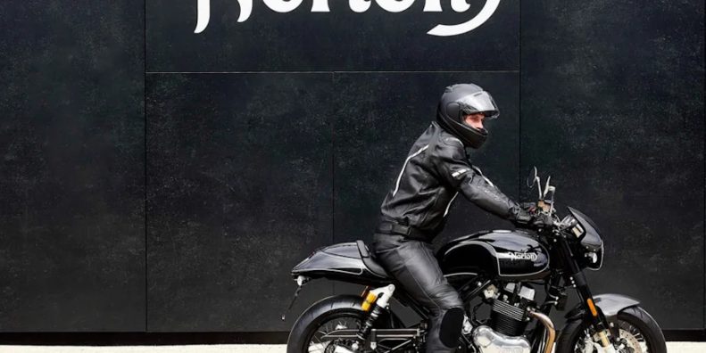 A motorcyclist in front of a sign.