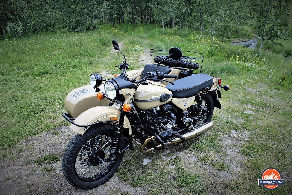 A view of a Ural Gear Up Sidecar on a motorcycle, on a field of patchy grass